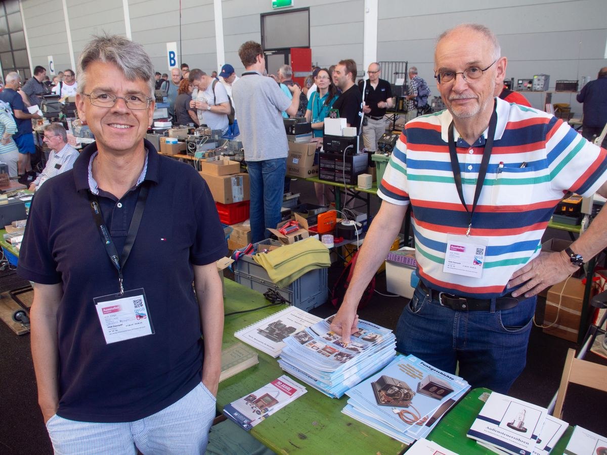 Menschen am GFGF-Messestand bei der HAM RADIO 2025 im Gespräch über historische Funkgeräte
